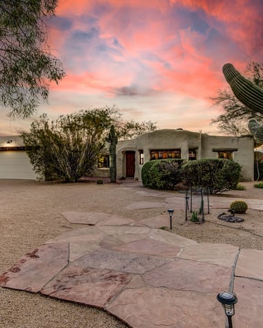 Desert home with white stucco exterior, saguaro cactus, and native landscaping at sunset