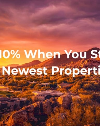 Desert landscape at sunset with promotional text overlay offering 10% discount on newest properties
