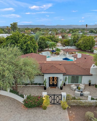 Aerial view of mid-century modern home with pool, surrounded by desert landscaping and mountains in distance
